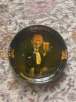 Front view showing the graphic of a waiter holding beer, text 'Hampden', and visible surface damage including residual white paper spots.