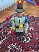 Front angle photo of complete 1999 McDonald's Inspector Gadget toy action figure showing mechanical accessories, hat with purple rotor, yellow watch, and detailed figure standing on carpet.