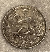 Front side of the Iran 1928 silver coin featuring the crowned lion with sun rays and wreath.