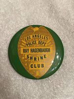 Front view of the round green and yellow Los Angeles Police Department Shriners Club pin badge featuring an eagle and text.