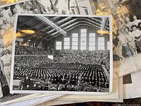 Large graduation photo showing hundreds of students in an auditorium with high arched windows and overhead lighting.