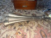 Side view of the four trumpet horns laid on a carpet showing the length and metal finish.