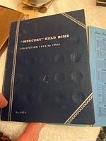 Cover of blue book labeled 'Mercury Head Dime Collection 1916 to 1945' showing book condition and title