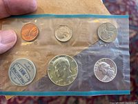 Photo of 1964 Philadelphia Mint coin set sealed in original plastic packaging showcasing five coins: penny, nickel, dime, quarter, and half dollar.