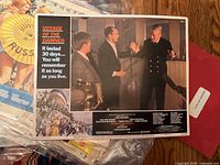 Photo of the Voyage of the Damned lobby card showing ship officers in discussion, includes text tagline "It lasted 30 days... you will remember it as long as you live."