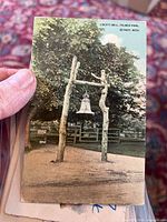 Front image of a vintage postcard showing Liberty Bell mounted on wooden frame in Palmer Park, Detroit, Michigan with trees in background