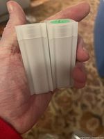 Photo of two white plastic coin rolls held in hand showing the shape and size of the coin rolls.