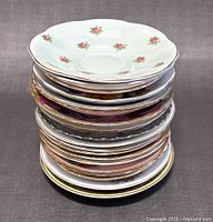 Stacked view of the saucers showing varied edge shapes, floral patterns, and some gold trim details.