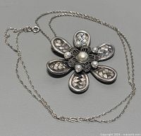 Full view of the necklace with flower pendant showing design and chain length.