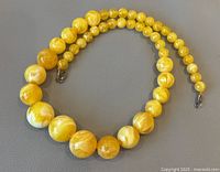 Full strand of graduated amber beads laid on grey background