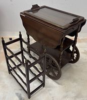 Tea cart with wheels, drop-leaf sides, removable tray on top, and matching wine rack beside it.
