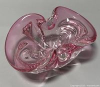 Top-down photo showing the freeform curved organic shape and pink tint of the thick glass bowl.