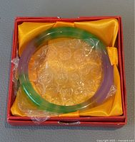 Natural jade bangle in original red and yellow silk-lined box, showing the bangle wrapped with bubble wrap.