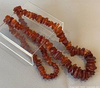 Full view of the natural raw amber necklace laid flat, showing the entire length and bead variation.