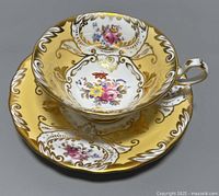 Front view of Royal Chelsea teacup on matching saucer, showing floral pattern and gold detailing on porcelain.