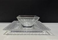 Clear glass bowl resting inside a square glass plate, showing overall set and scale.