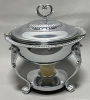 Front view of the assembled metal candle chafing dish with lid showing ornate legs and heart-shaped lid handle.