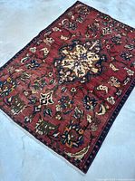 Full view of the vintage Persian Bakhtiari rug showing overall pattern and colors on a concrete surface.
