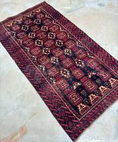 Full view of the rectangular Baluchi rug laid flat showing the pattern and condition.