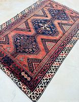 Angled view of full rug laid on light floor, showing entire pattern and shape.