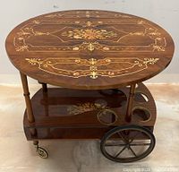 Front perspective view of entire tea cart with drop leaves extended, showing top surface, two-tiered shelves and wheels