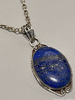 Close-up of oval lapis lazuli pendant stone set in silver frame with chain.