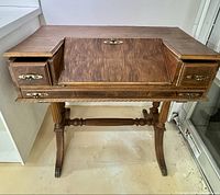 Front view of vintage secretary desk showing closed fold-down writing surface and drawers.