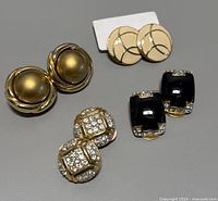 Four pairs of vintage clip-on earrings displayed on gray background showing size and details