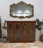 Front view of cabinet with wood frame, four glass doors and brass hardware