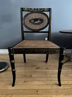 Full front view of chair showing overall shape, cane seat, Greek key apron and tapered legs.