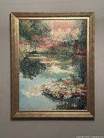 Front view of framed painting showing landscape scene of house and pond with water lilies