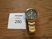 Full view of Fossil watch on wooden surface with lot tag showing lot number 250.