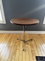 Front view of round wooden top table with metal tripod base