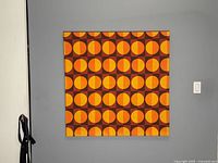 Full view of mid-century modern optical art wall hanging on gray wall, showing overall design and size.