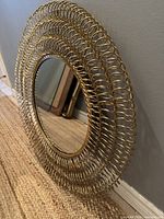 Close-up oblique angle showing the brass looped concentric ring frame and central glass mirror surface, highlighting the design and condition.