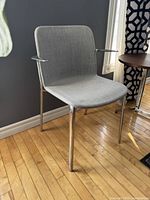 Side angle view of the Modern Max Design APPIA armchair showing aluminum legs and grey upholstered seat and back.