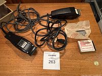 Two black Oster Duo-Top Type 616-91 hair clippers with attached cords, extra cutting blade, unopened blade box, and loose blade laid out on wooden surface