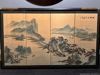 Four-panel folding screen showing continuous Chinese landscape painting with mountains, water, houses, trees, and boats.