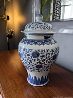 Front angle view of vintage Chinese blue and white porcelain ginger jar with detailed floral patterns, lid on.