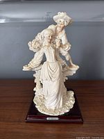 Front view of the vintage Giuseppe Armani Capodimonte courting couple sculpture showing the detailed figures of a woman and man on a wood base.