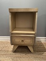 Front view of the vintage mid century nightstand showing open shelf and drawer with geometric design and round metal knob.