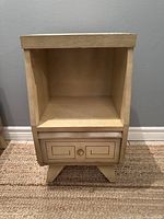 Full front view of the vintage mid century nightstand showing the open shelf, drawer with geometric design, and angled legs.