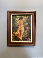 Full view of the framed oil painting featuring a nude woman standing in water, holding a tree branch with greenery in the background.