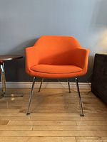 Front view of the orange armchair showing seat, arms, and legs