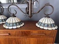 Pair of vintage Tiffany style double ceiling lights with stained glass shades in white, blue, and amber diamond pattern on tabletop.