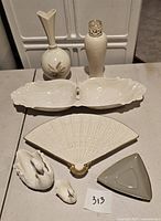 Wide view of seven Lenox porcelain items including two vases, divided dish, swan figurines, fan-shaped dish and triangular dish.