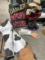 Photo of leather cow pattern chaps and Halloween decoration items on display including skeleton figure and haunted house sign