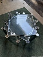 Top view of the nesting tables showing the clear glass top and chrome frame with circular accents at the top of legs.