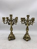 Pair of brass candelabras shown side by side on a white background, full view to show overall size and condition.
