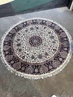 Full view of circular floral area rug on concrete floor showing overall pattern and condition.
